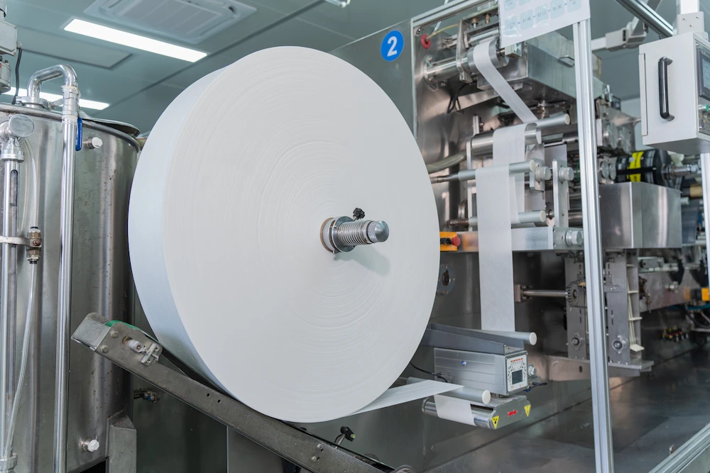 a large roll of sneaker wipes on a processing machine that cuts it into packet sizes