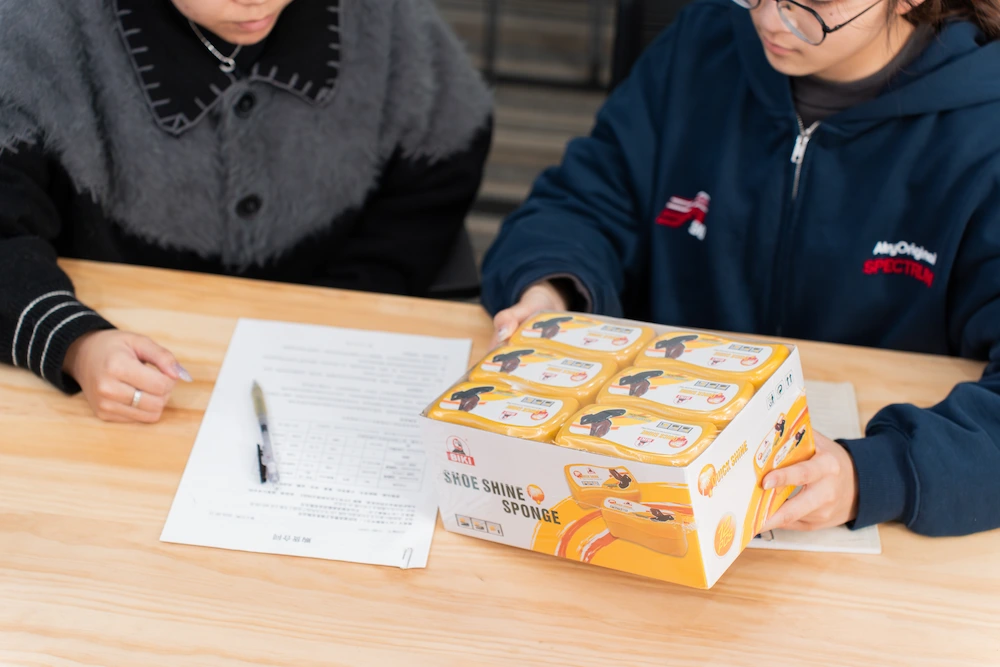 quality control team inspects a package of shoe shine sponges to check the packaging quality, durability, and visual appeal