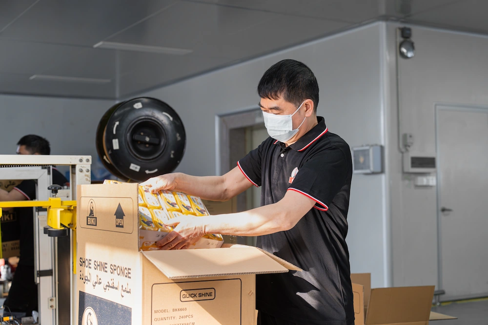 BIKI employee packing a set of shoe shine boxes into carton boxes in preparation for shipping