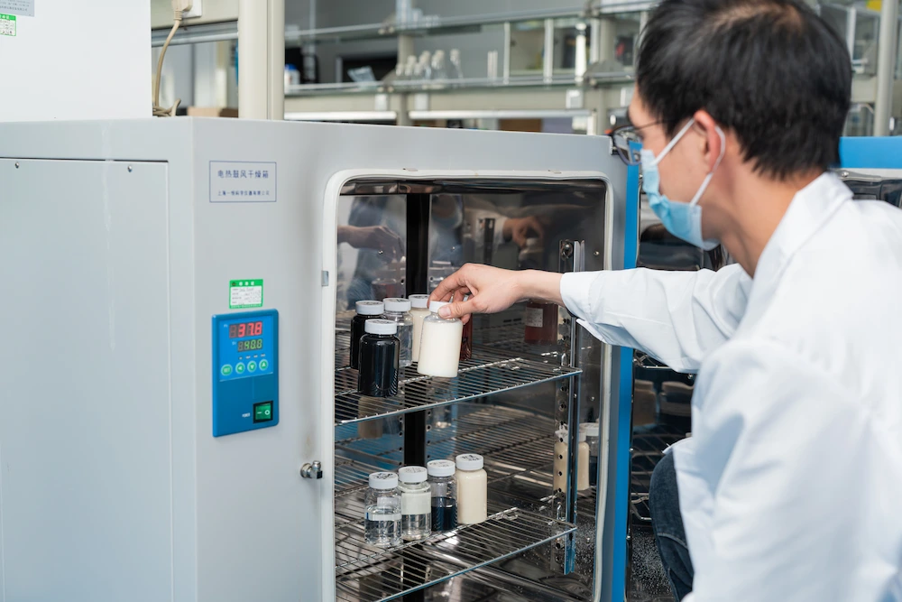 a seasoned quality inspector places bottles of shoe cleaning formula on machine that checks their stability