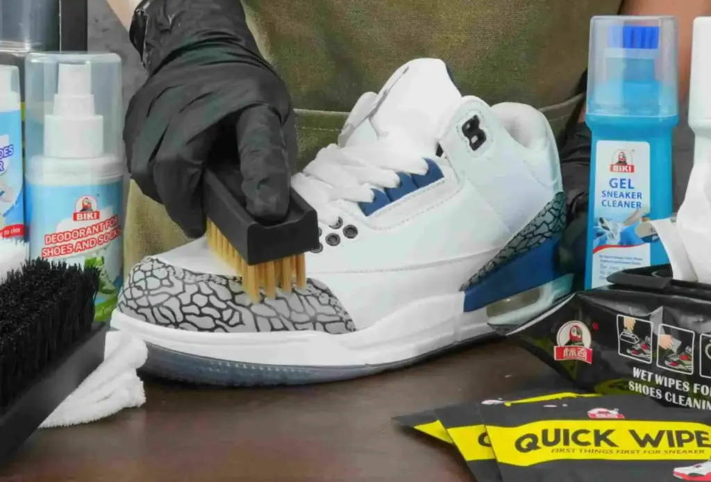 A man is cleaning sneakers with a cleaning brush
