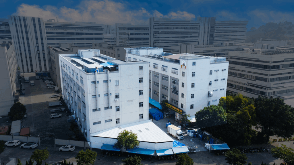 Aerial view of BIKI's 30,000㎡ eco-friendly factory - producing premium Sneaker Cleaner, Leather Care Kits & Waterproof Sprays. White industrial buildings with blue loading zones & logistics trucks visible.