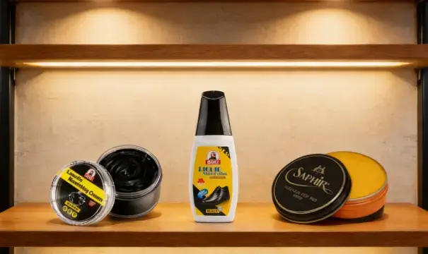 Three premium shoe care products (black shoe cream, liquid polish, and neutral wax) neatly arranged on a wooden shoe store display shelf.